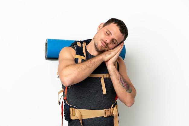 Homme d'alpiniste brésilien avec un gros sac à dos sur fond blanc isolé faisant un geste de sommeil dans une expression adorable