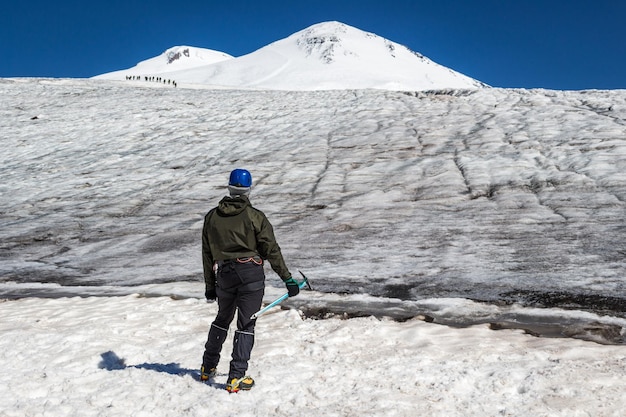 Homme d'alpiniste en crampons et casque avec piolet à la recherche des sommets des montagnes de l'Elbrouz. Groupe d'alpinistes sur un fond. Mode de vie actif, liberté, concept de réussite.