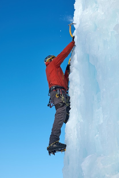 Homme alpiniste avec piolet escaladant un grand mur de glace Sports de plein air Portrait