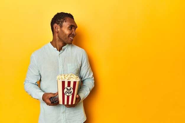 Un homme américain d'origine africaine tenant du pop-corn dans un décor de studio jaune