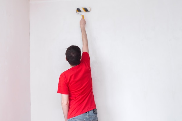 homme amorçant le mur avec une réparation de rouleau de l'intérieur avec espace de copie