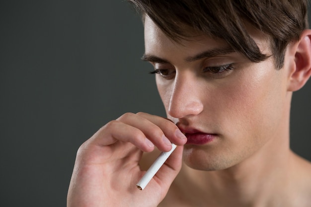 Homme androgyne posant avec cigarette dans sa bouche