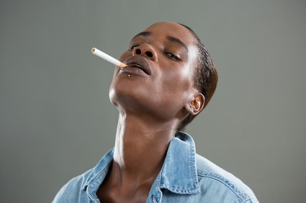 Homme androgyne posant avec cigarette dans sa bouche