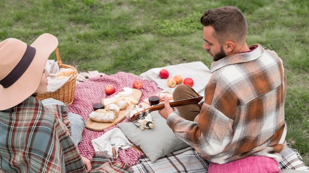 Photo homme à angle élevé jouant de la guitare pour petite amie