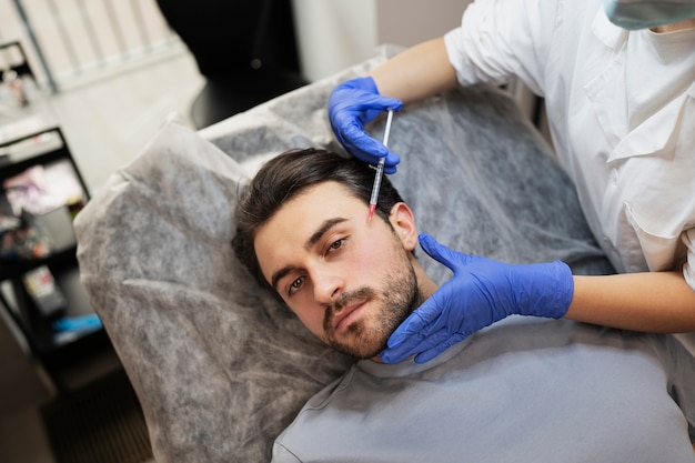 Photo homme à angle élevé recevant une injection d'acide hyaluronique