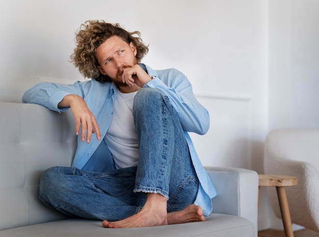 Photo homme anxieux plein coup pensant sur le canapé