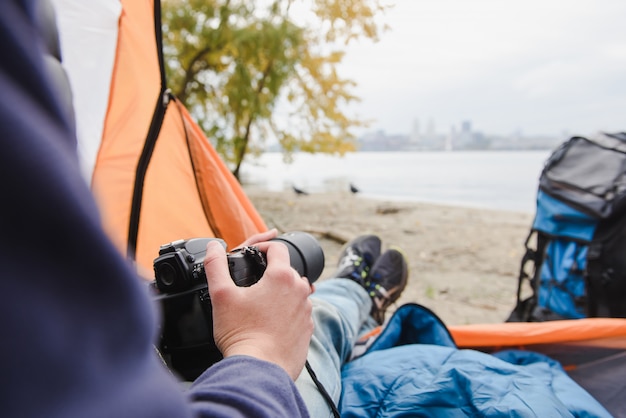 Homme avec un appareil photo dans une tente de camping