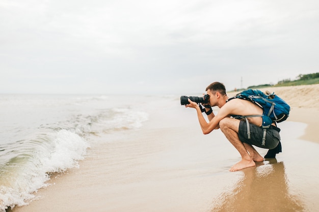 Homme avec appareil photo prenant une photo de la mer. Photographe homme implantation sur la plage et prise de photo de la nature.