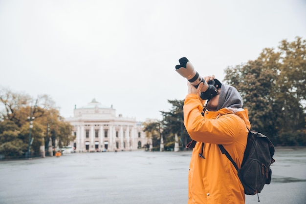 Homme avec appareil photo professionnel et grand objectif prenant une photo de l'architecture de la ville