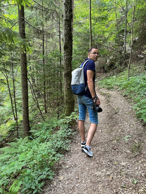 Un homme avec un appareil photo et un sac à dos se promène dans la forêt