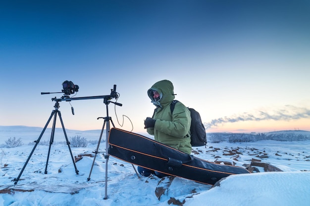 Homme avec appareil photo sur trépied prenant des photos accélérées dans la toundra arctique