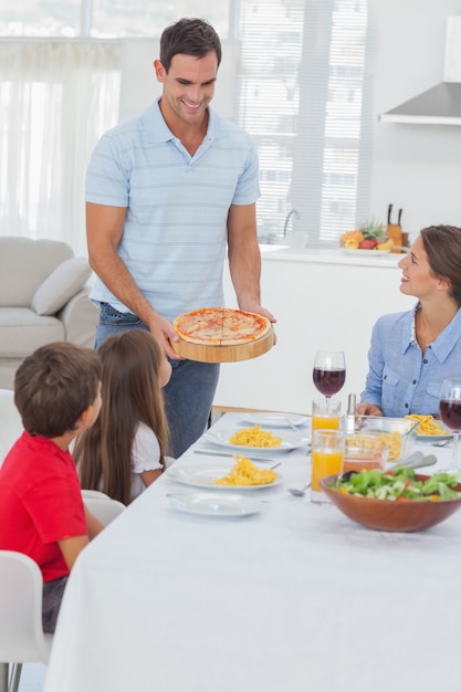 Homme apportant une pizza à sa famille