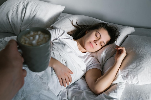 Un homme apporte une tasse de café à une femme au lit le matin