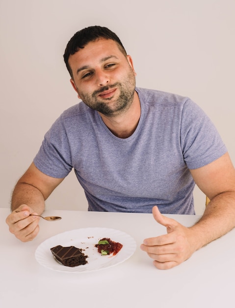 Homme appréciant un gâteau au chocolat avec de la confiture de fraises