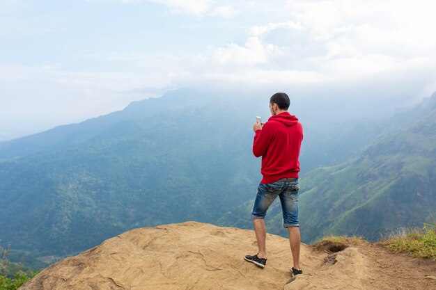 Photo un homme appréciant le paysage de montagne au bord d'une falaise