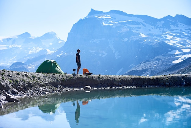 Homme appréciant le paysage de montagnes près de la tente