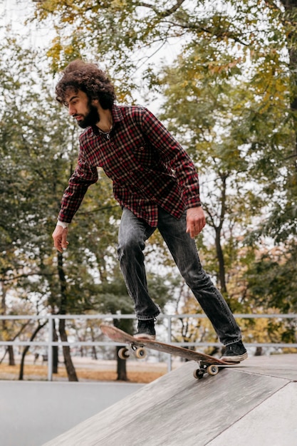 Photo homme appréciant la planche à roulettes dans le parc de la ville