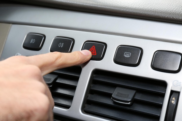 Homme appuyant à la main sur le bouton d'alerte d'urgence sur le gros plan de la console de la voiture