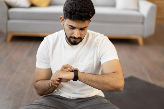 Photo homme arabe définissant une montre de fréquence cardiaque pendant l'entraînement à domicile