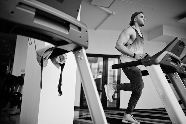 Homme arabe en forme et musclé courant sur tapis roulant dans la salle de gym.