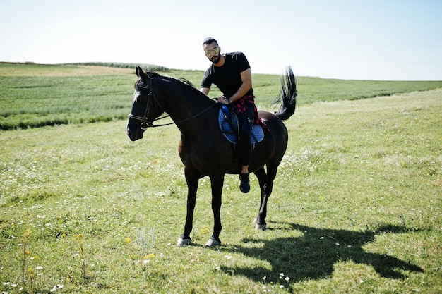 L'homme arabe à grande barbe porte des lunettes noires et des lunettes de soleil à cheval arabe.