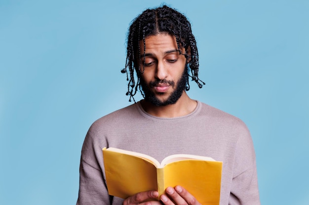 Un homme arabe sérieux, concentré, lisant des livres et pensant.