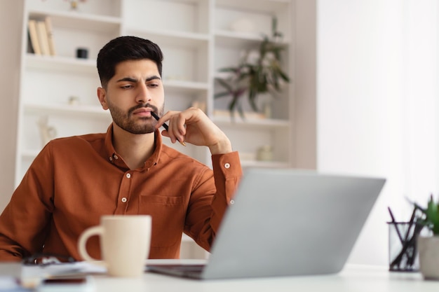 Homme arabe utilisant un ordinateur portable assis au bureau au bureau