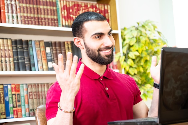 Homme arabe utilisant un ordinateur portable pendant ou lors de réunions pour étudier et enseigner via des canaux en ligne