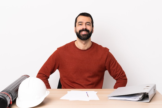 Homme d'architecte caucasien avec barbe dans une table en riant.