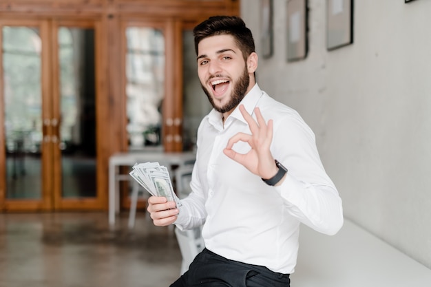 Homme avec de l'argent montrant un geste ok