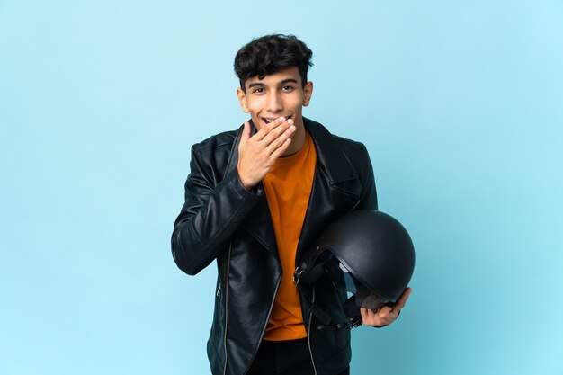 Homme argentin avec un casque de moto heureux et souriant couvrant la bouche avec la main