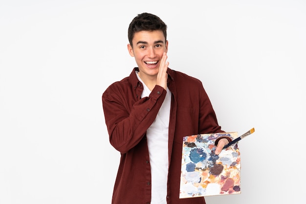 Homme artiste adolescent tenant une palette sur le mur blanc chuchoter quelque chose