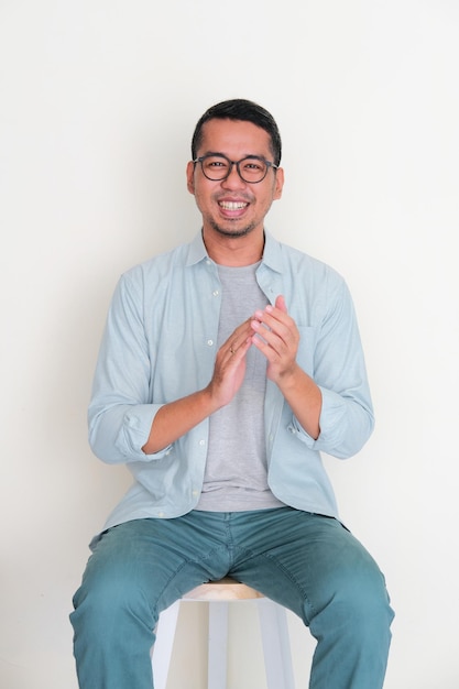 Un homme asiatique adulte applaudit assis sur un banc