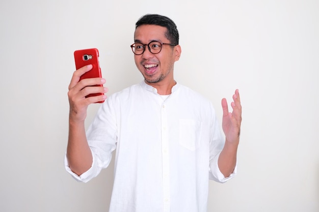 Homme asiatique adulte montrant un geste excité en regardant son téléphone portable