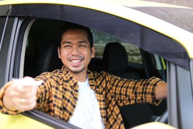 Homme asiatique adulte souriant amical tout en donnant son ticket de parking