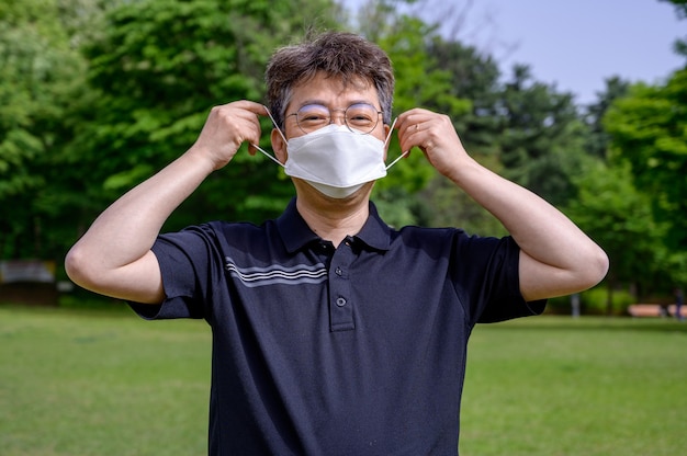 Homme asiatique d'âge moyen portant un masque facial sur la pelouse.