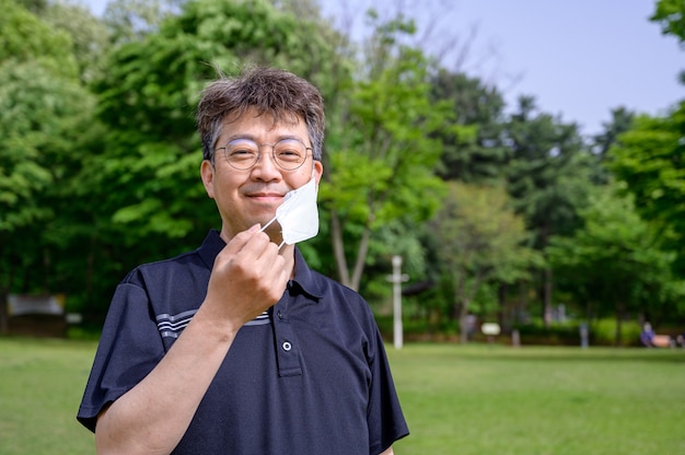 Homme asiatique d'âge moyen portant un masque facial sur la pelouse.