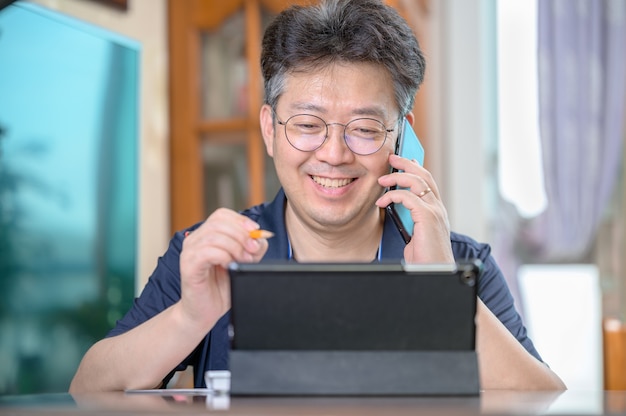 Homme asiatique d'âge moyen travaillant à la maison. Concept de télétravail.