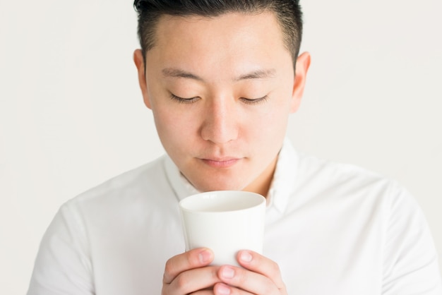 Homme asiatique agréable, sentant le café fraîchement moulu