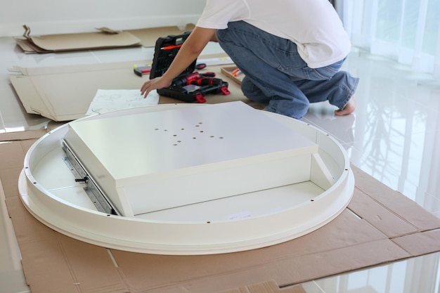 Homme asiatique assemblant des meubles de table blancs à la maison