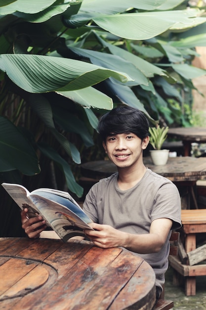 Homme asiatique assis dans un café en lisant un livre