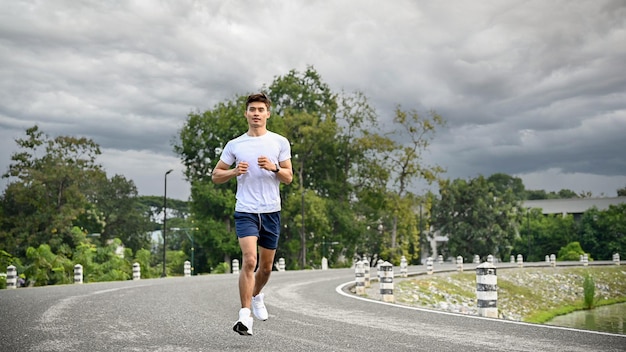 Photo homme asiatique athlétique en vêtements de sport et chaussures de course professionnelles courant à l'extérieur