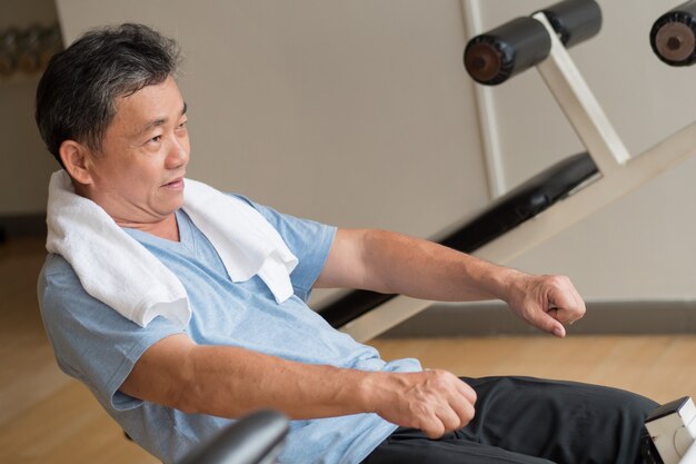 Homme asiatique en bonne santé, heureux, souriant, bien-être senior positif travaillant sur un muscle ab dans la salle de sport