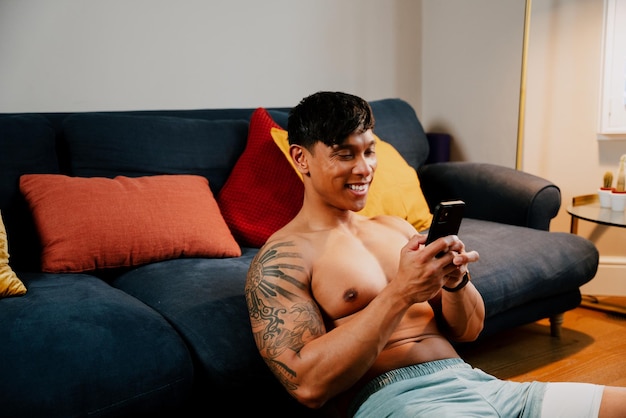 Homme asiatique avec bras tatoué jouant sur téléphone portable