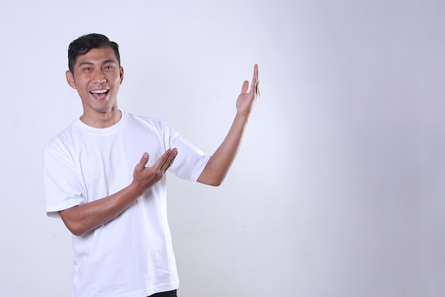Un homme asiatique en chemise blanche avec une expression joyeuse et présentant quelque chose