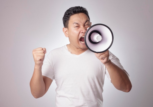 Un homme asiatique criant avec un mégaphone criant fou criant fou soutenant un concept motivant