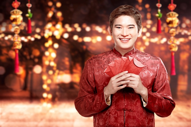 Homme asiatique dans un costume de cheongsam tenant des enveloppes rouges