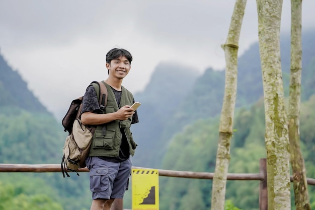 Homme asiatique debout seul tenant le téléphone dans la nature fraîche de la montagne verte