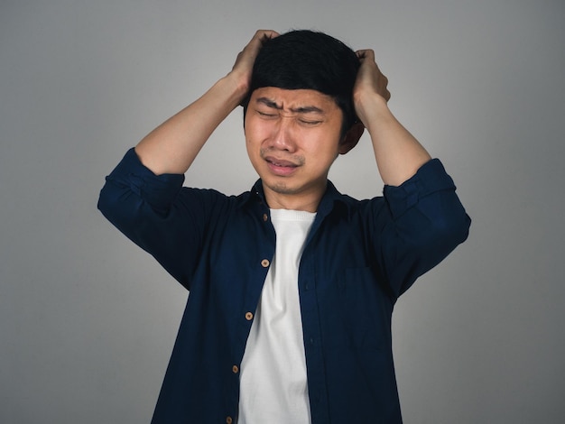 Un homme asiatique déprimé a mal à la tête et pleure sur sa vie