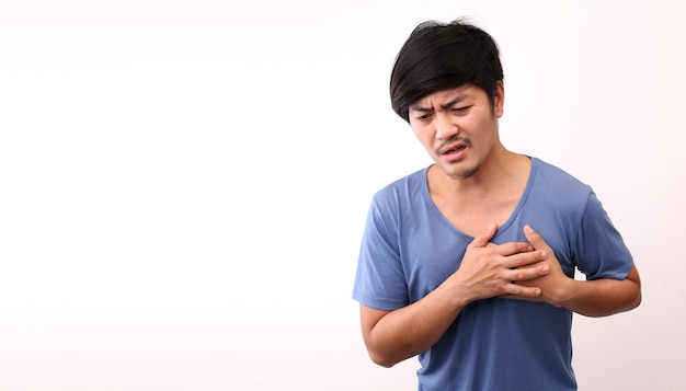 Homme asiatique avec douleur cardiaque sur fond blanc en studio avec espace de copie.